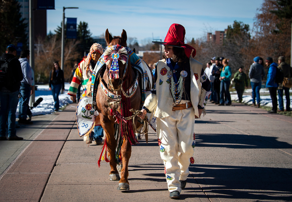 A member of the American Indian community is pictured with their horse.