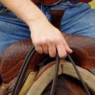 Person on a horse holding reins togther with one hand and their pointer finger looped through