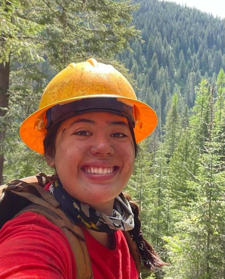 Image of Lexi Smith in a forest with a red shirt and orange protective helemt.