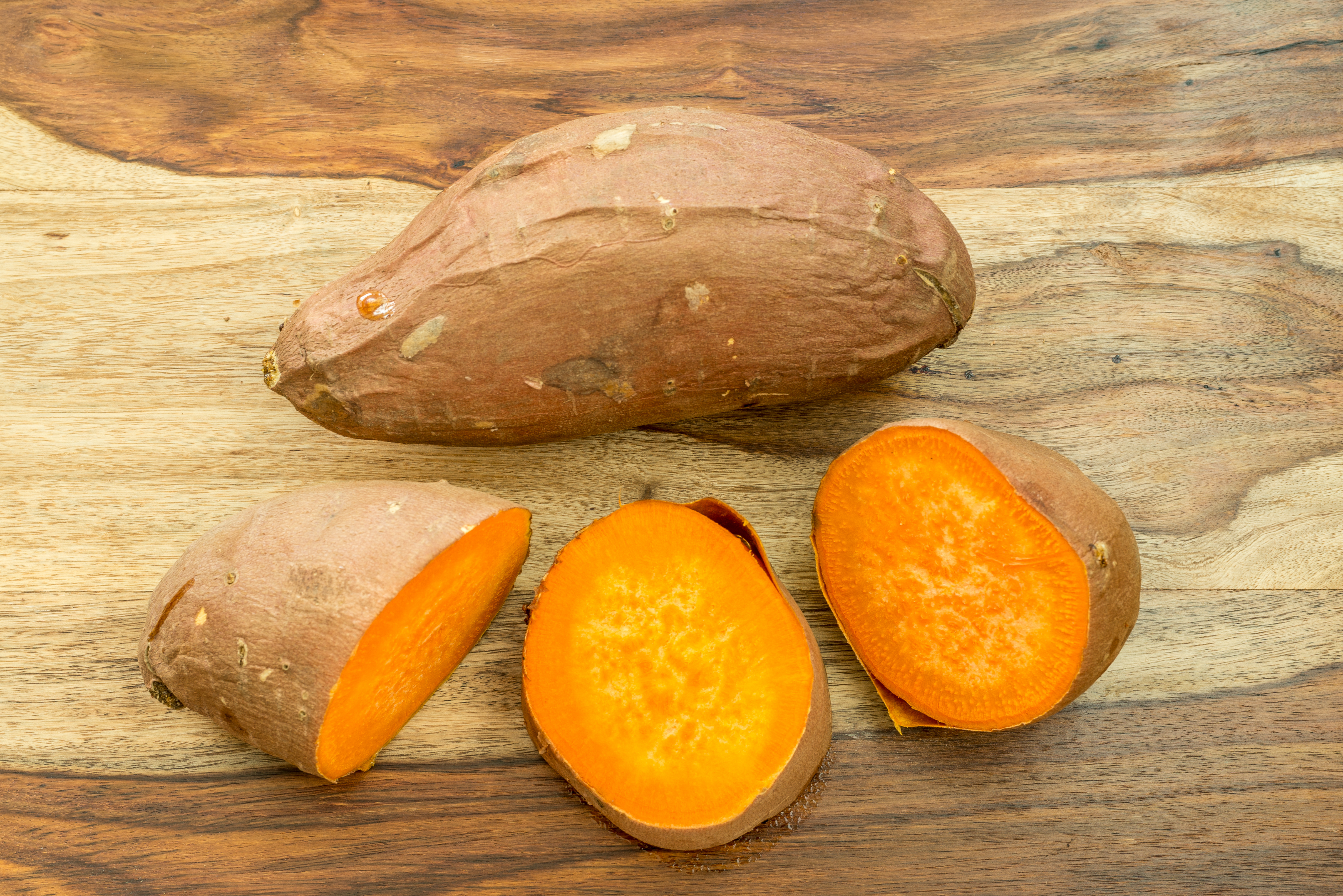 A whole sweet potato and another sweet potato sliced into three parts.