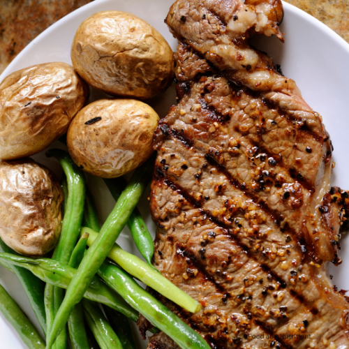 Image of a grilled sirloin steak, pared with roasted potatoes and green beans. 