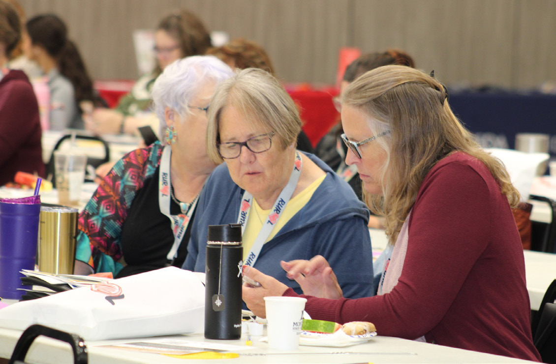 Two older women are discussing in a conference setting.