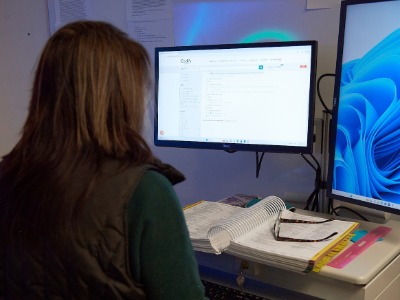 A woman works on a computer with her back to the camera