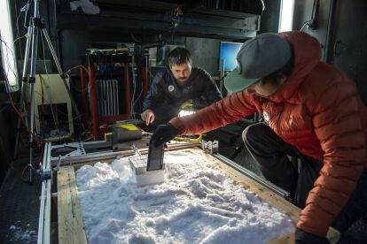 Researchers conduct an experiment with snow inside a controlled lab environment using scientific instruments.