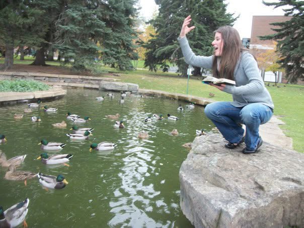 Female student is feeding ducks at the MSU duck pond