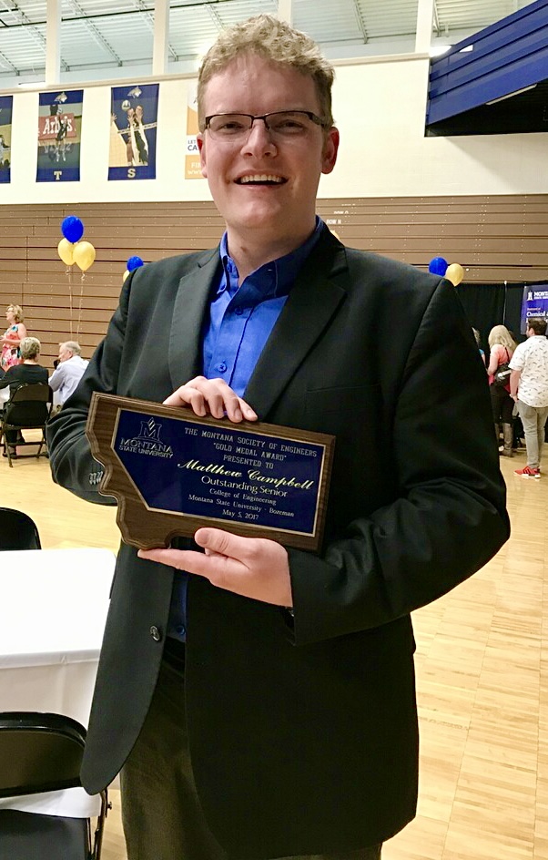 Male student holding an award that says outstanding Senior in the College of Engineering
