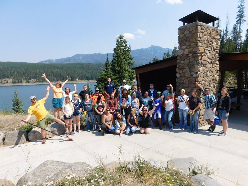 TRiO scholars in front of the Hyalite Pavilion at the Hyalite Reservoir with a small lake and mountains in the background